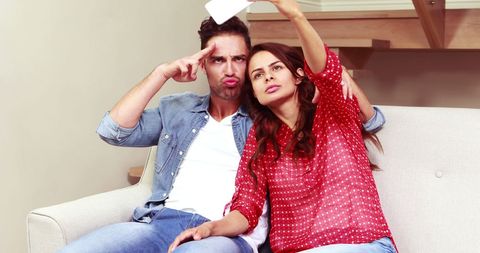 Happy Couple Taking a Humorous Selfie on Sofa Indoors
