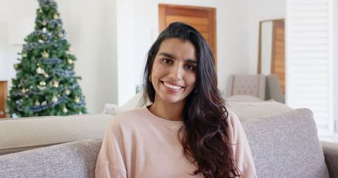 Smiling Woman Relaxing Near Decorated Christmas Tree