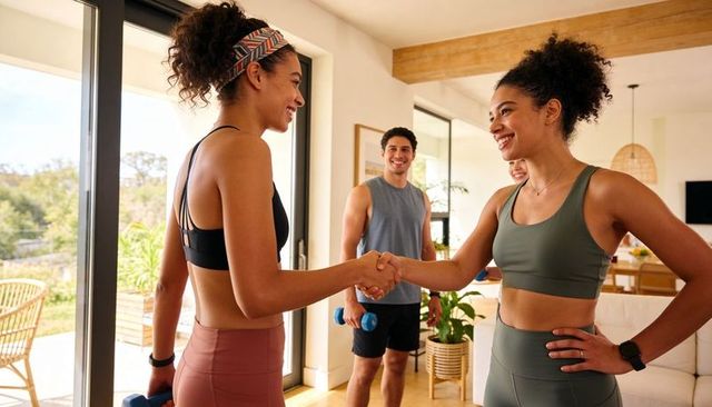 Sunlit home workout greeting: two women shaking hands after group fitness session