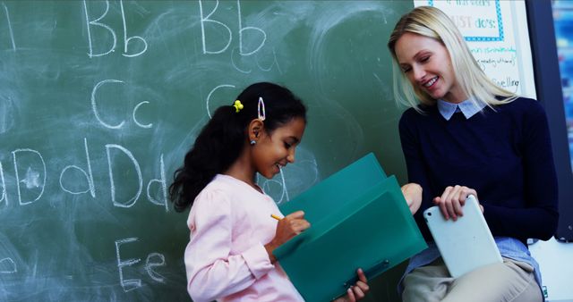 Teacher Helping Young Student With Assignment Near Chalkboard Classroom - Download Free Stock Images Pikwizard.com