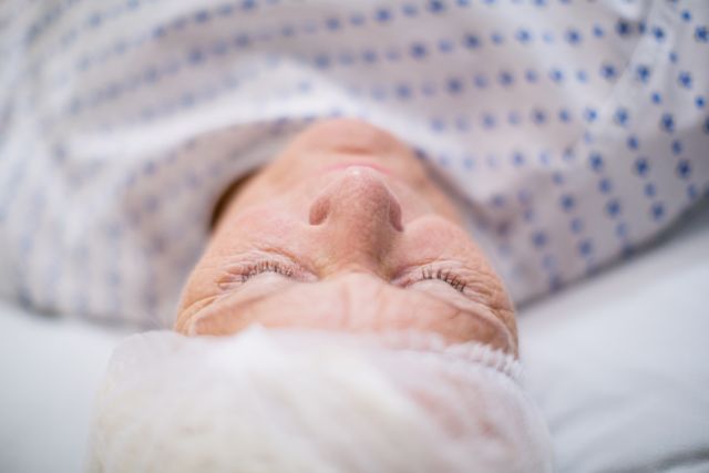 Senior woman patient sleeping on bed in hospital room