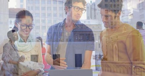 Collaborative team examining laptop through reflective urban glass