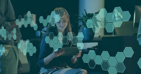 Smiling businesswoman using tablet with holographic ar hexagon interface in modern office