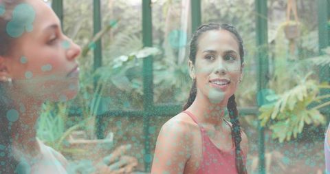 Pacific islander woman talking in greenhouse wellness class wearing red tank top