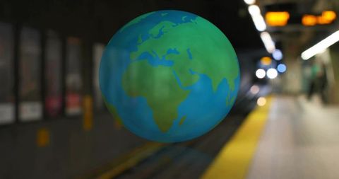 Hovering earth globe above metro platform with yellow safety edge and neon bokeh