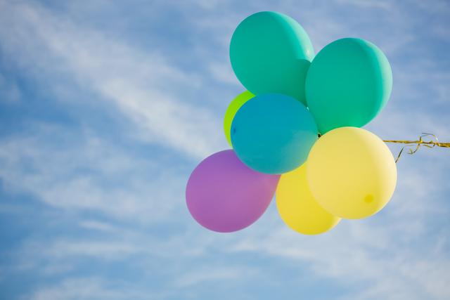 This image shows a bunch of pastel-colored balloons floating against a clear blue sky. It can be used for promoting parties, celebrations, outdoor events, or festive gatherings. Perfect for greeting cards, invitations, and social media posts celebrating joyful occasions.
