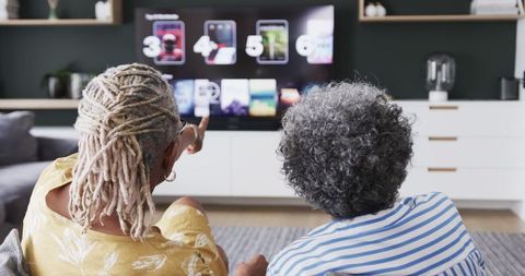 Senior Friends Choosing TV Show Together in Living Room