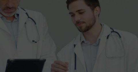 Doctors Collaborating and Reviewing Data on Tablet in Consultation Room