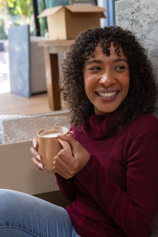 Young Woman Enjoying Coffee Break Amidst Moving Boxes
