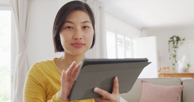 Portrait of happy asian woman using tablet in living room - Download Free Stock Photos Pikwizard.com