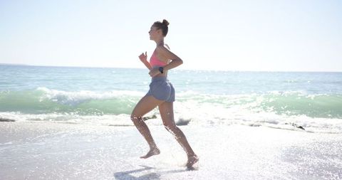 Young Woman Jogging on Sunny Beach Shoreline