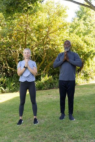 Mature couple practicing mindfulness meditation in sunny garden for wellness