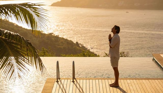 Man praying at golden sunset on infinity pool deck overlooking ocean