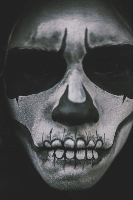 Close-up view of person with face painted like a skeleton, capturing spooky theme perfect for Halloween events, horror movie posters, costume party promotions, and social media campaigns focusing on eerie or spooky themes.