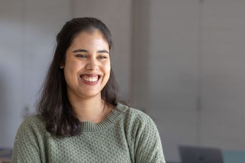 Smiling woman wearing sage knit sweater during casual modern office meeting