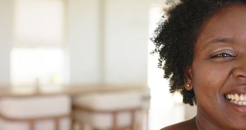 Natural-light portrait of African American mid-adult woman smiling in bright kitchen with copy space