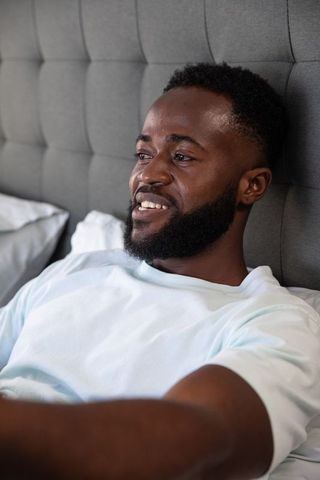 Relaxed man smiling in bedroom for tranquil leisure time