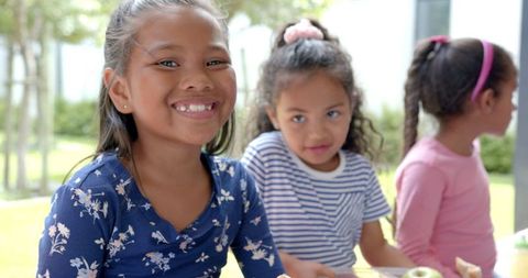 Children Smiling While Enjoying Outdoor Picnic Lunch Together