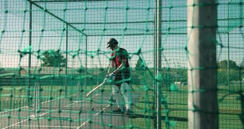 Indian cricket batter practicing in outdoor net cage during coaching and training session