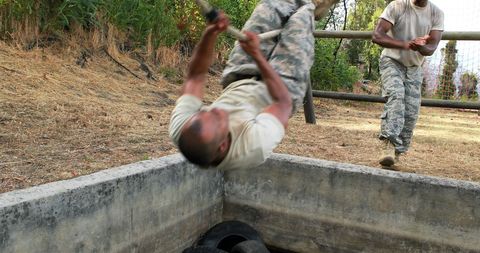 Military officer performing pull-ups in outdoor training drill