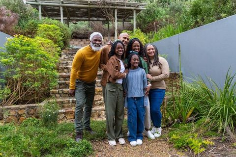 Multigenerational african american family smiling together in backyard garden on stone steps