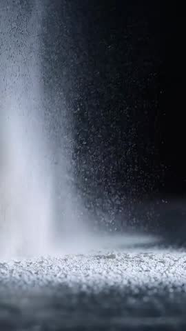 Vertical slow motion powder plume rising from surface with dramatic studio lighting
