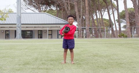 Youthful enthusiasm: boy with yoga mat on sports field