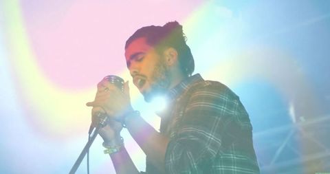 Performer singing joyously under colorful lights at live concert