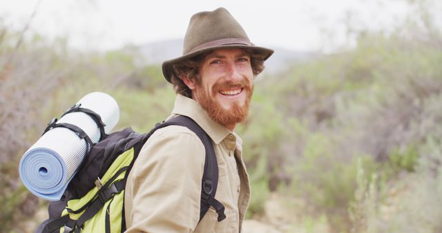 Portrait of smiling bearded caucasian male survivalist trekking through wilderness with backpack. exploration, travel and adventure, survivalist in nature.