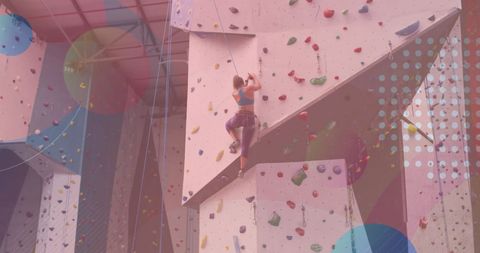 Caucasian woman rock climbing indoors with abstract overlay