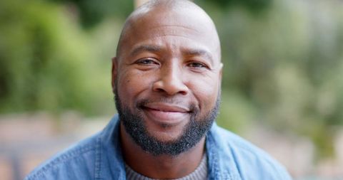 Smiling mature african american man wearing denim jacket and knit sweater in park