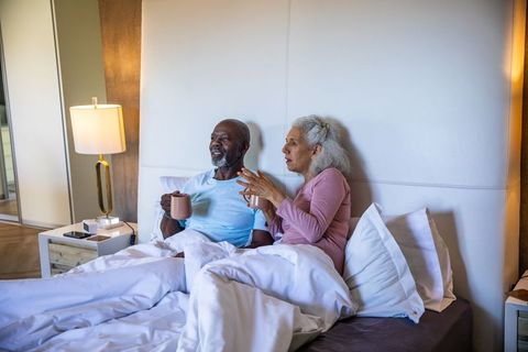 Senior Diverse Couple Relaxing Together with Morning Coffee in Bed