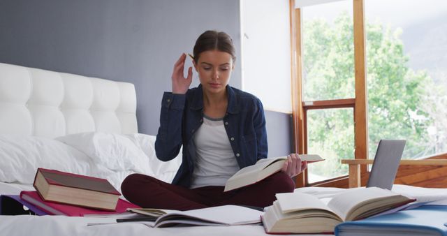 Focused young woman studying with books and laptop on bed - Download Free Stock Images Pikwizard.com