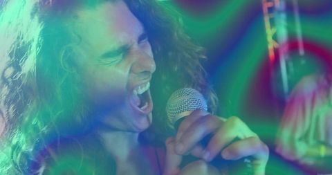 Captures an energetic moment of a performer with curly hair singing passionately into a microphone at a lively nightclub. Vivid stage lights and musical instruments in the background set a dynamic scene ideal for promoting live music events, concerts, nightclub promotions, and entertainment industry visuals.