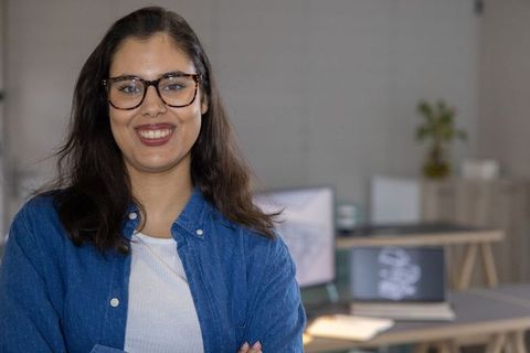 Young professional woman smiling with crossed arms in modern coworking office