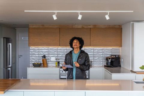 African american man using tablet at modern minimalist kitchen island with appliances