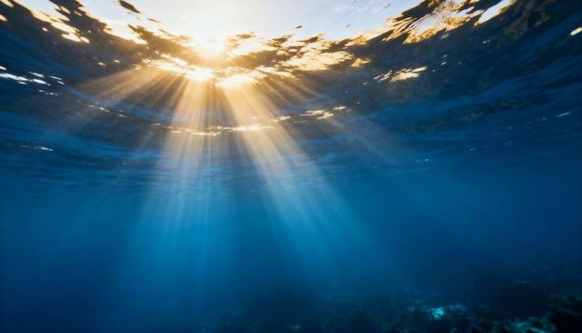 Sunbeams penetrating ocean surface casting golden rays through deep blue water