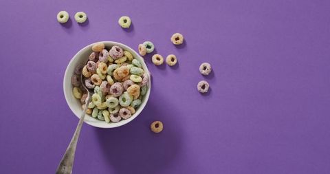 Colorful breakfast cereal in bowl on purple surface