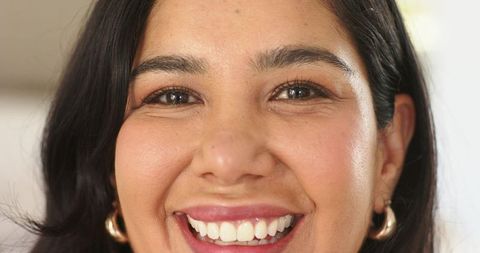 Smiling woman showing teeth wearing gold hoop earrings close-up portrait headshot