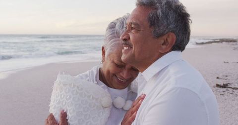 Content Senior Couple Embracing on Tranquil Beach at Sunset