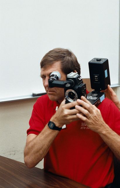 STS-34 Atlantis, Orbiter Vehicle (OV) 104, Pilot Michael J. McCulley squints while looking through ARRIFLEX camera eye piece during camera briefing at JSC. McCulley rests part of the camera on his shoulder as he operates it.