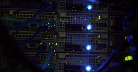 Rack-mounted server blades with blue leds and teal ethernet cables for data center