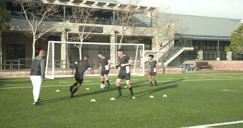 Team Soccer Training Session with Coach Guiding Drills on Field