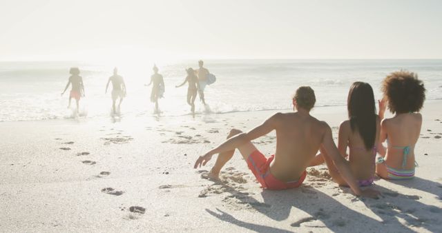 Friends Enjoying Sunset at Beach, Relaxing on Sand - Download Free Stock Images Pikwizard.com