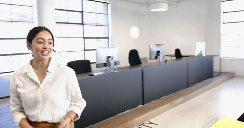 Smiling Businesswoman in Modern Office Setting with Computers