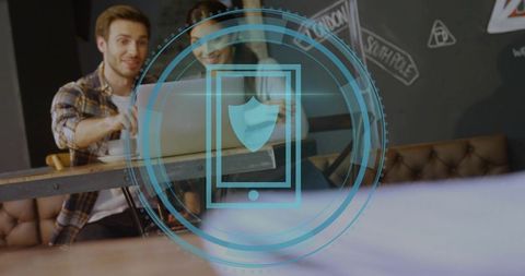 Coworkers collaborating in cafe with laptop and holographic mobile security shield overlay