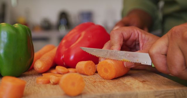 Close-up of hands chopping carrots and bell peppers on a wooden cutting board. Perfect for blogs, recipes, and healthy cooking content. Highlights fresh vegetable preparation and culinary skills in the kitchen.