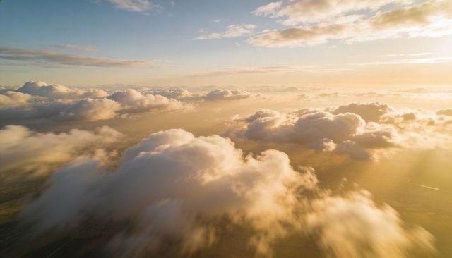Drifting Golden-Hour Cumulus Clouds Over Sunlit Horizon Aerial Panorama