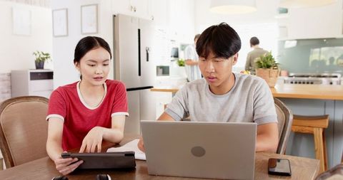 Asian Family Collaborating on Gadgets in Modern Kitchen