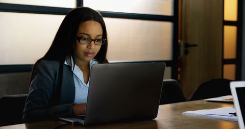 Businesswoman Concentrating on Laptop in Modern Office Environment